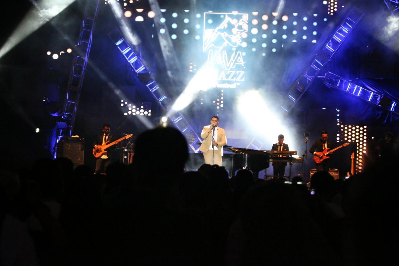 Andmesh bernyanyi dengan menggunakan jas berwarna coklat